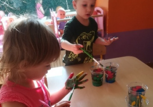 Chłopiec i dziewczynka malują dłonie farbami